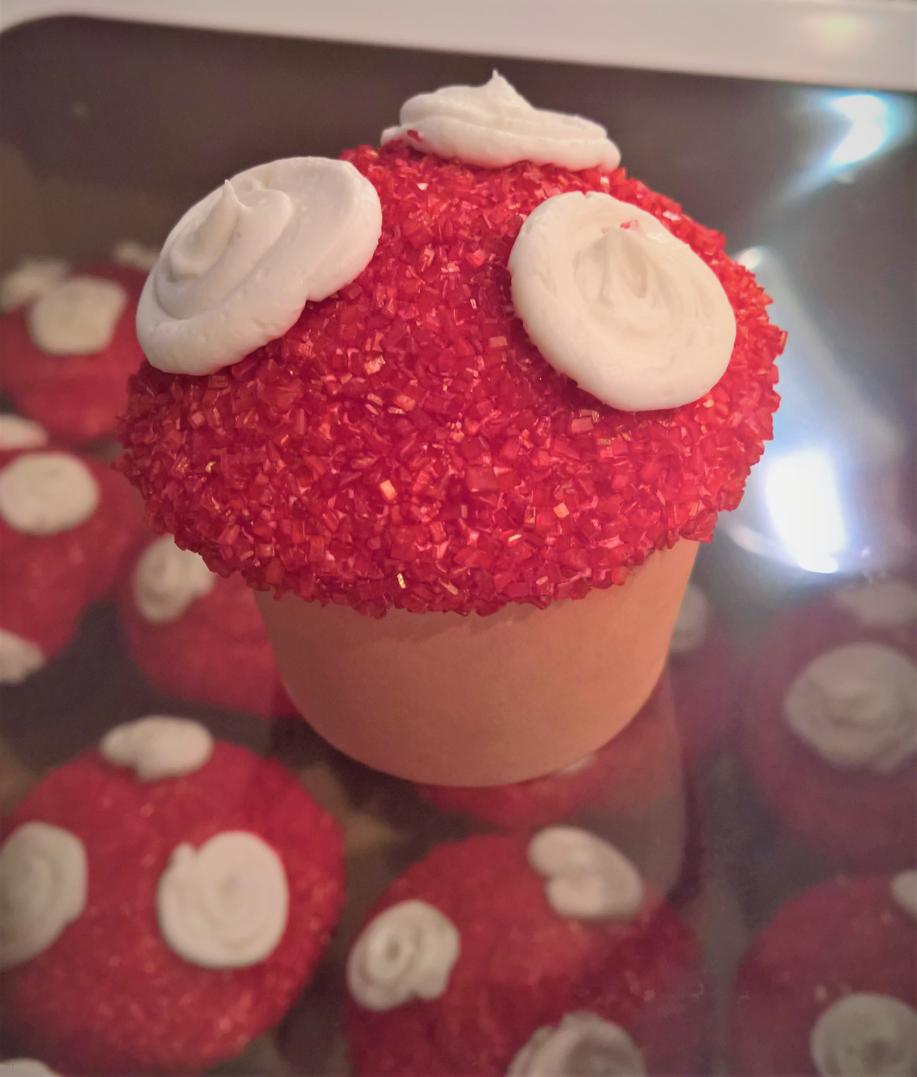 Mario mushroom vanilla cupcakes decorated in red icing then rolled in red s...